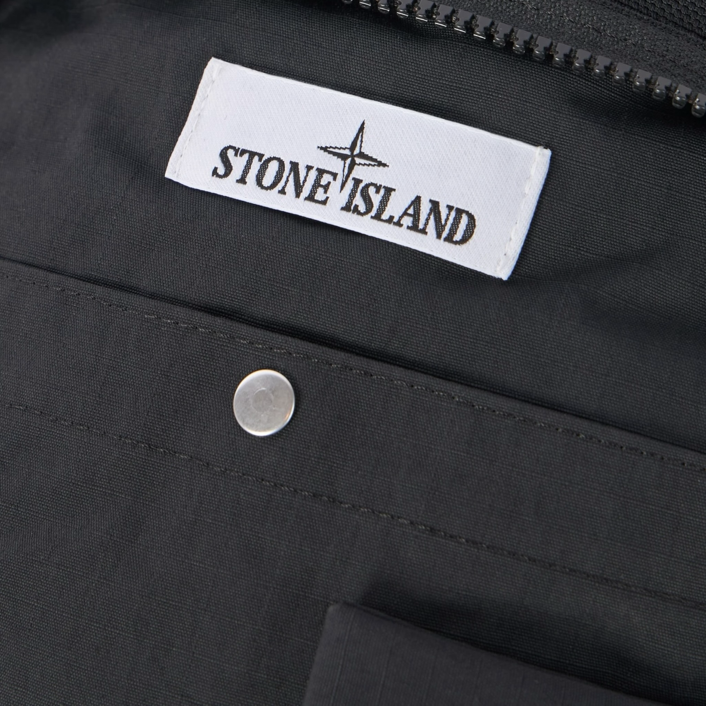 Urban Saints Stone Island black nylon crossbody bag with navy blue textured panel and embossed logo.