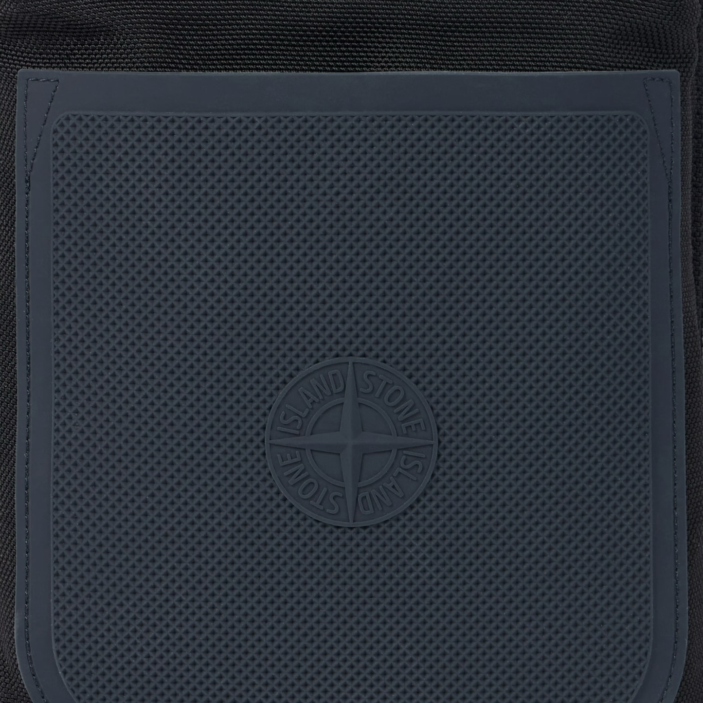 Urban Saints Stone Island black nylon crossbody bag with navy blue textured rubber panel and embossed logo.