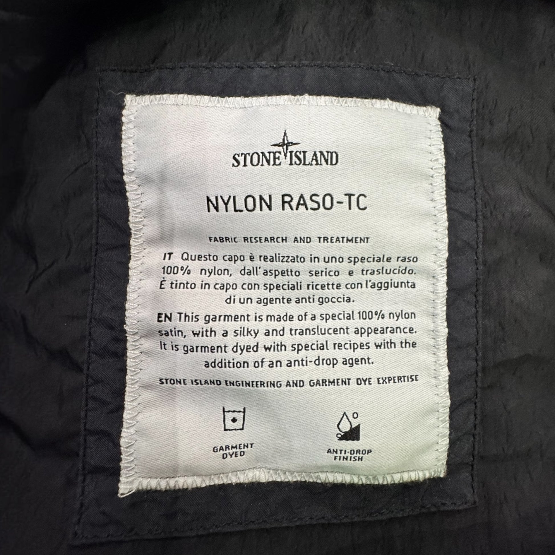 Urban Saints Stone Island Nylon Raso-TC garment label detailing fabric research and anti-drop finish on black nylon